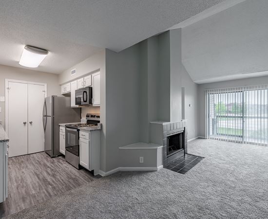 an empty living room and kitchen with a fireplace and a window